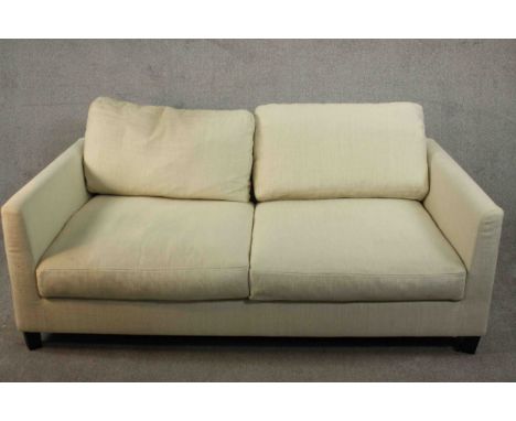 Meridiani, Italy; a contemporary two seater sofa with loose back and seat cushions, upholstered in cream fabric and raised on