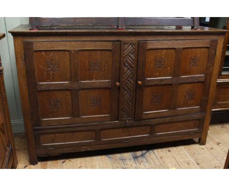 Oak plank top Arts &amp; Crafts cupboard having two carved panel doors above a fall front door, 122cm by 188cm by 63cm.