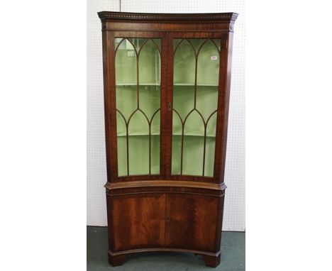 A GEORGIAN DESIGN MAHOGANY BOW FRONT FULLSTANDING CORNER CUPBOARD, having dentil cornice, with twin astragal glazed doors, ov