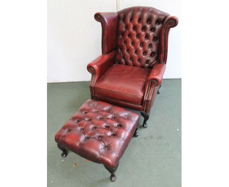 A RED LEATHER WING BACK EASY CHAIR, with button back, on cabriole legs, together with a matching footstool 