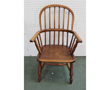 A CHILD'S PROVINCIAL WINDSOR STICK BACK ARMCHAIR, having elm seat, on ring turned supports united with stretchers 