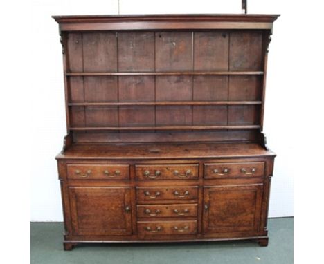 A GEORGIAN OAK DRESSER WITH PLATE RACK, the base fitted drawers and cupboards with brass handles, quarter column decoration, 