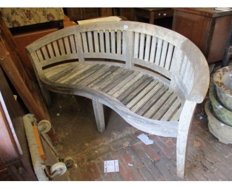 20th Century teak garden bench of curved and shaped design with a slatted back and seat