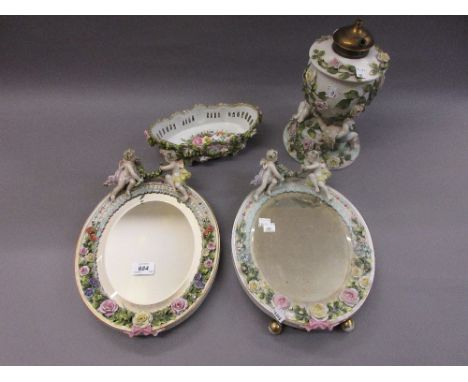 Continental porcelain oval floral encrusted table mirror with cherub surmount, together with a similar mirror, an oil lamp an