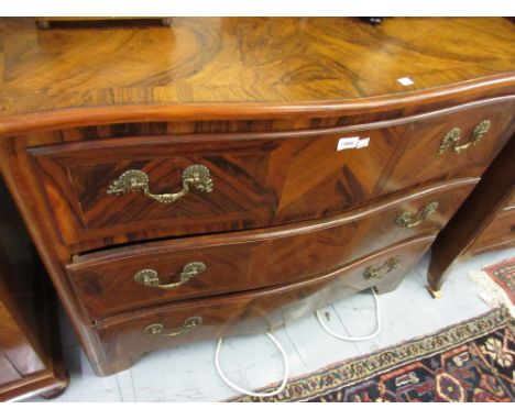 20th Century Continental figured walnut and crossbanded commode with three serpentine shaped drawers, ornate cast brass handl