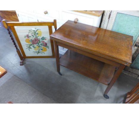 An oak barleytwist embroidered firescreen and an oak fold over trolley 