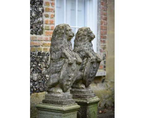 A PAIR OF COMPOSITION STONE HERALDIC LIONS  20TH CENTURY  Lions modelled seated  114cm high, the bases 32.5 x 33.5cm   Condit