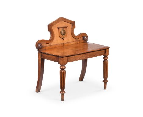 A GEORGE IV FIGURED OAK HALL SEAT IN THE MANNER OF GILLOWS, CIRCA 1825 The back centred with a cartouche centred with a crest