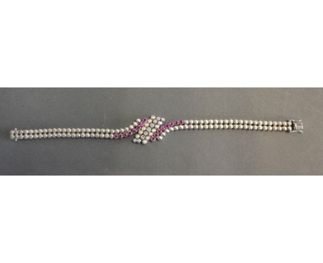 An 18ct. White Gold Diamond and Ruby Set Bracelet of Crossover Form, with two bands of rubies and a central band of diamonds,