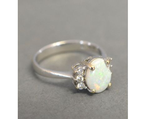 A Platinum Opal and Diamond Ring with an oval claw set opal flanked by six diamonds within a pierced setting