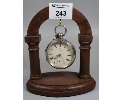 Silver open faced pocket watch marked Best English made warranted with enamel face and Roman numerals on a wooden architectur