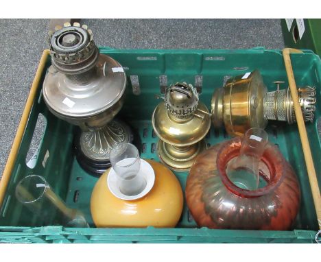 Box with two brass oil lamp bodies, one ornate metal oil lamp body, three glass chimneys, a pink glass shade and an opaque ye