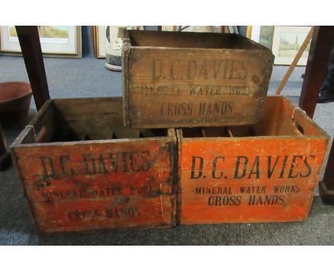 A pair of vintage stained pine two handled bottle crates marked 'D.C. Davies Mineral Waterworks Cross Hands'. Together with a