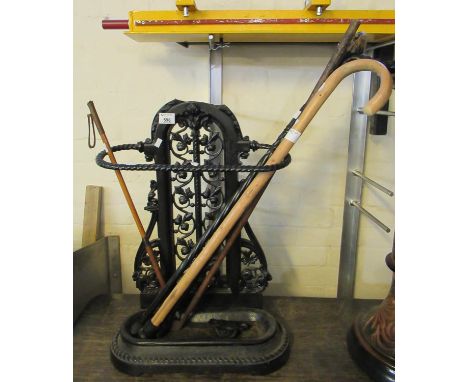 Victorian style cast iron stick stand with pierced foliate decoration, together with a collection of walking sticks and a rid