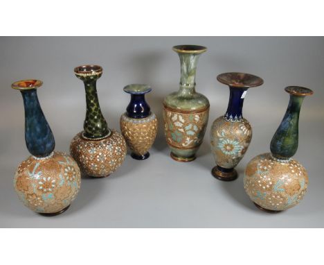 A collection of six Doulton stoneware vases of varying designs, some of baluster and some of ovoid form, decorated with gildi