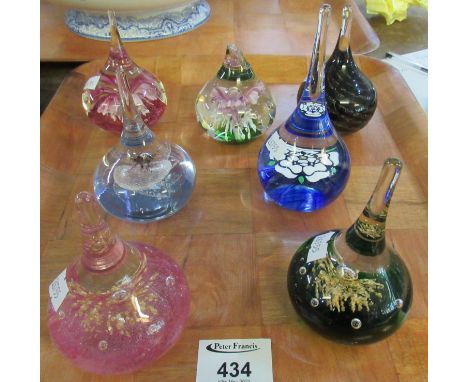Tray containing seven teardrop shaped paperweights in various colours and designs, some with floral designs inside, one marke