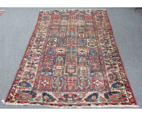 A Kurdish carpet with central field of forty-five rectangular geometric panels within a multi-figured and stylised floral bor