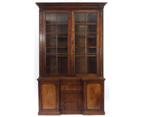 A late Regency oak bookcase, the moulded cornice with knulled border, fitted adjustable shelves enclosed by a pair of glazed 