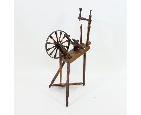 A cherry wood spinning wheel, the bobbin turned wheel with brass rim, on turned legs, 96cm high