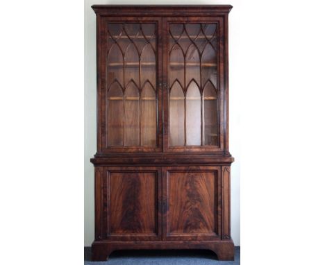 A Regency mahogany bookcase, the glazed upper section with lancet shaped astragals above a cupboard base on bracket feet, 214