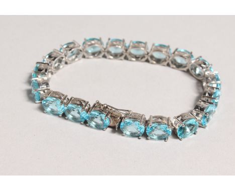 A SILVER BLUE TOPAZ SET LINE BRACELET.