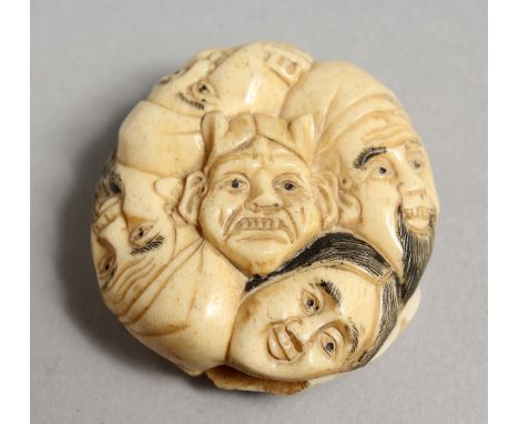 A JAPANESE CARVED BONE FACES NETSUKE. 1.5ins.