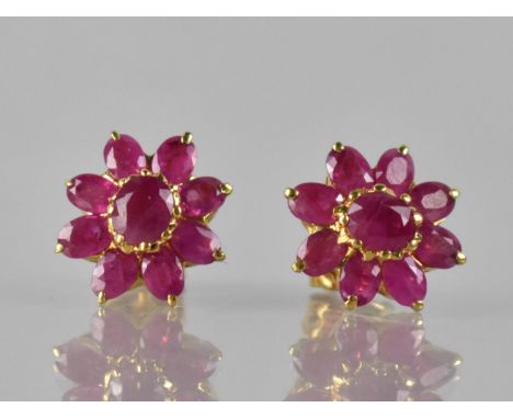 A Pair of Ruby and Gold Coloured Metal Cluster Earrings, Central Claw Set Oval Cut Ruby Measuring 5mm by 4mm and Surrounded b