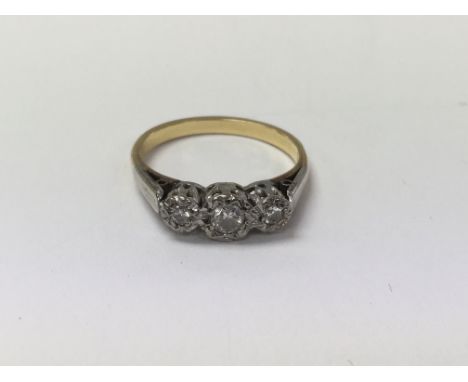 An unmarked gold and platinum ring set with three small brilliant cut diamonds. Measuring approximately size N.