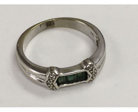A white gold ring inset with three baguette cut emeralds. Ring size K