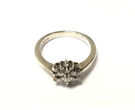 A 9carat white gold ring set with a star pattern of raised brilliant cut diamonds (one stone missing) Ring size L-M