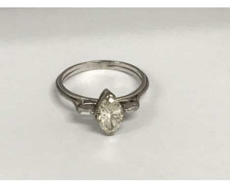 An unmarked white gold ring inset with a Marquise diamond flanked by smaller diamond. Size R .