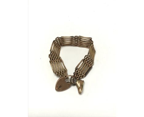 A 9ct gold gate bracelet with a heart clasp and shoe pendant. Weighing approximately 24.5G.