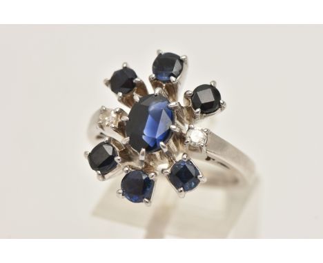 A WHITE METAL SAPPHIRE AND DIAMOND CLUSTER RING, set with a central oval cut sapphire, flanked with two single cut diamonds a