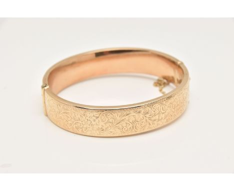 A 9CT GOLD HINGED BANGLE, decorated to one side with a floral and foliate pattern, fitted with a push piece clasp and additio