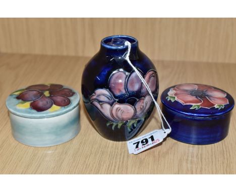 A GROUP OF THREE MOORCROFT POTTERY ITEMS comprising two lidded trinket pots, diameter 7cm, including one anemone on cobalt bl