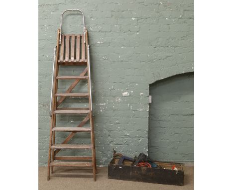 A pair of old wooden steps with chrome safety rails along with a box of tools, G clamps, saws, spanners and electric drill an