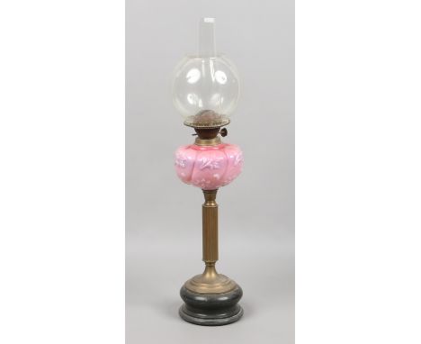 A Victorian oil lamp with pink opaque glass font over a brass and slate base.