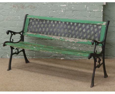 An iron and painted wooden garden bench with lattice back rest.