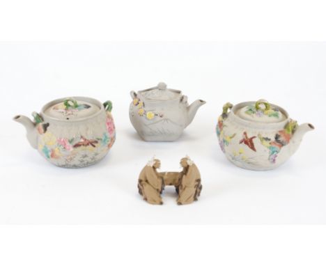 Three Japanese bisque teapots,  each with relief moulded decoration of flora and fauna with polychrome enamel decoration, hei