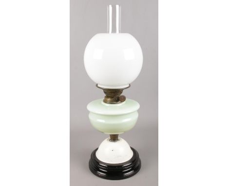 A small brass oil lamp, on mint green support with clouded glass shade.  
