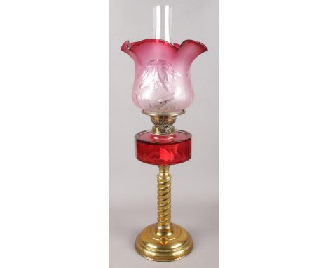 A cranberry glass oil lamp, on twisted brass support with turned base.  Shade has been repaired.