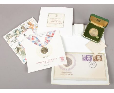 Three commemorative British coins/medals. Includes silver Royal Wedding medallic first day cover, Commonwealth Games commemor