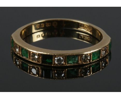 An 18ct gold diamond and emerald half eternity ring. Size M. 2.52g.  Chips to some emeralds. First emerald missing corner of 