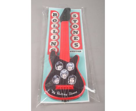 A Rolling Stones plastic toy guitar in original packaging.  