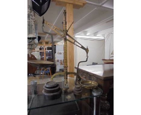 A set of old brass balance scales with weights.
