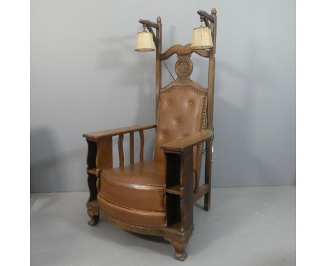An early 20th century Arts & Crafts style reading chair, with button-back faux-leather upholstered seat, integrated book shel