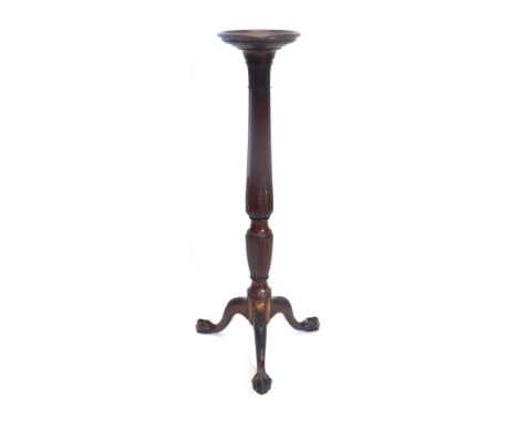 A mahogany plant stand or torchere, the circular dish top on a part turned reeded and leaf carved column, with leaf carved tr