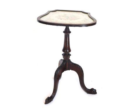 A walnut occasional table, the cartouche shaped tilt top inset with woolwork tapestry, on a turned column and leaf carved tri
