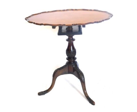 A mahogany tilt top occasional table, the oval pie crust top on a bird cage with leaf carved baluster column, on leaf carved 
