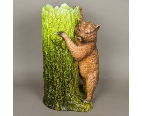 A late Victorian Bretby pottery stick standModelled as a brown bear with inset glass eyes leaning on a green glazed tree trun